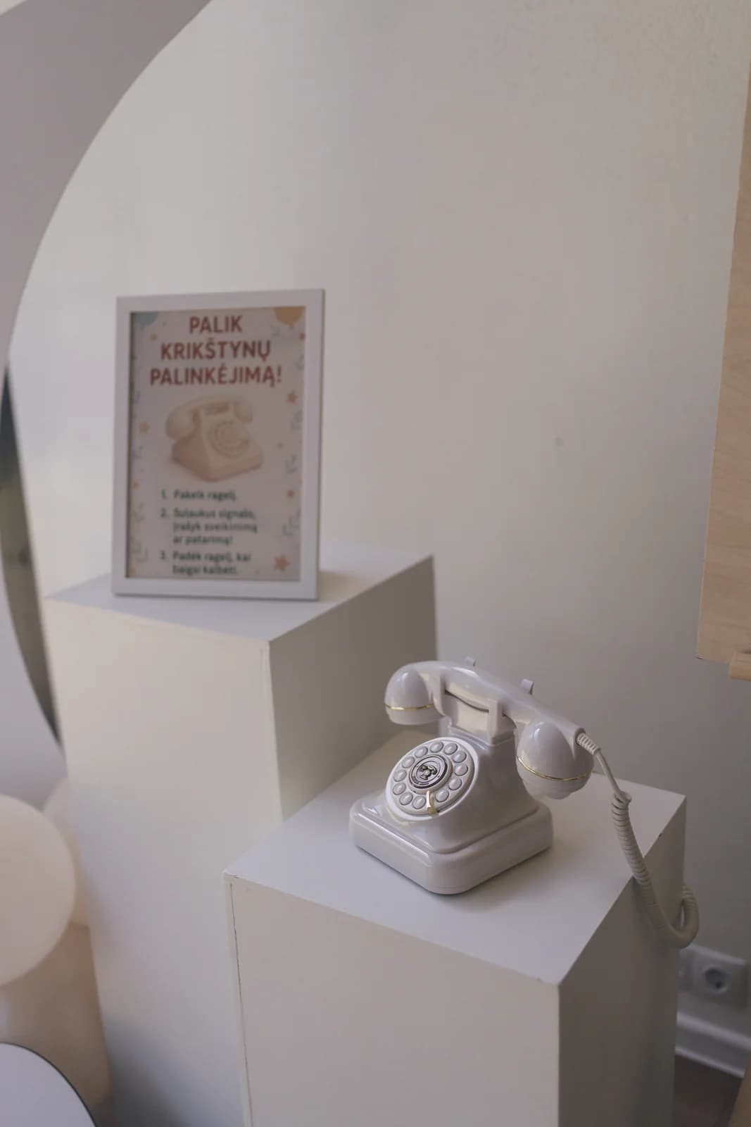 Telefonas ant stalelio su gėlėmis ir dekoracijomis